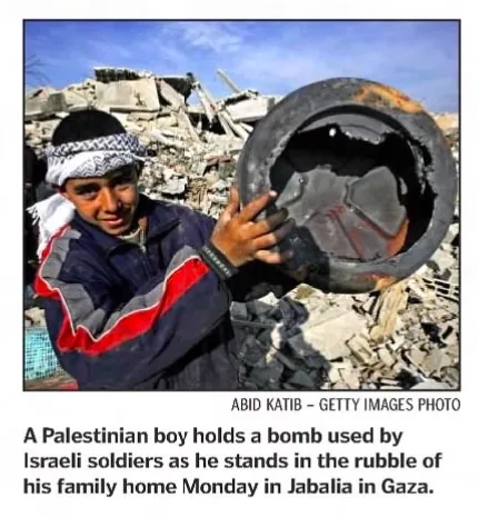 A Palestinian boy holds a bomb used by Israeli soldiers as he stands in the rubble of his family home Monday in Jabalia in Gaza &mdash; The Gazette, 1 February 2003