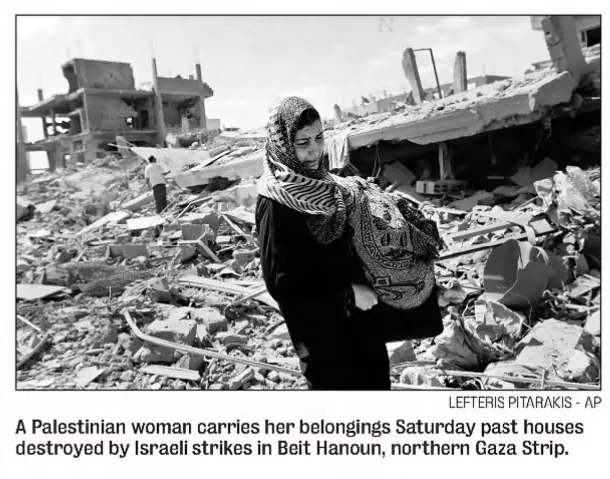 A Palestinian woman carries her belongings Saturday past houses destroyed by Israeli strikes in Beit Hanoun, northern Gaza Strip — The News & Observer, 27 July 2014