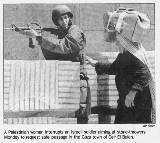 A Palestinian woman interrupts an Israeli soldier aiming at stone-throwers to request safe passage in the Gaza town of Deir El Balah — Chicago Tribune, 5 April 1994