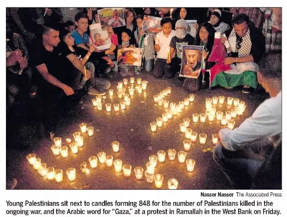 Young Palestinians sit next to candles forming 848 for the number of Palestinians killed in the ongoing war, and the Arabic word for 'Gaza', at a protest in Ramallah — The Sacramento Bee, 26 July 2014